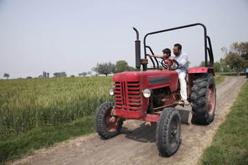 Little boy showing something to father while sitting in tractor 