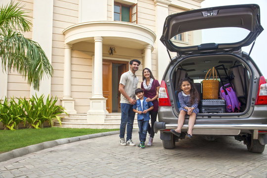 Family standing beside open boot of parked car to go on vacation	