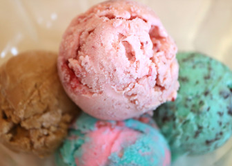 Closed up four scoops of ice cream in a glass bowl, with selective focus and blurred background 