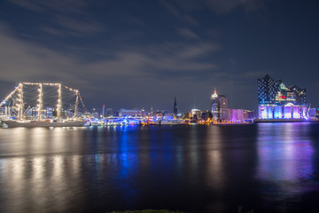 Fototapeta na wymiar Hamburg, Germany, Panorama of the Harbour at night. With the colored illuminated music hall at Christopher Street Day