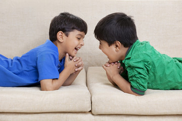 Happy brothers lying on sofa 
