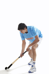 Young man in sportswear playing hockey isolated over white background