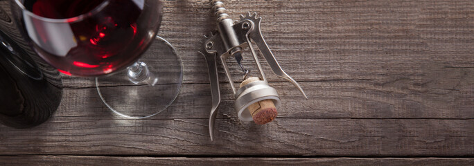 Corkscrew and a glass of wine on an old wooden table © Chepko Danil