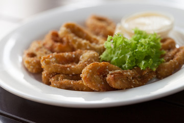 Squid sliced in rings fried in batter with sesame seeds with leaves of green salad