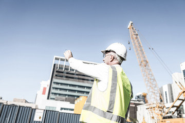 Senior foreman in glasses doing his job at building area on sunn