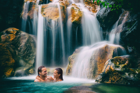 Waterfall couple relaxing in natural pool in tropical nature forest. Romantic getaway in hawaiian destination people swimming in travel vacation.