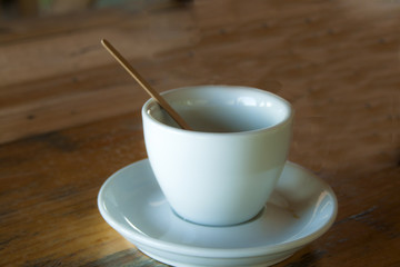 An empty coffee cup and a stick stand on a table