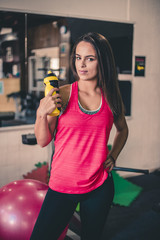 Attractive young brunette posing at the gym, holding water bottle