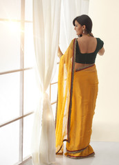 Woman in a saree looking out a window