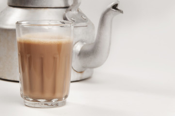 Glass of chai with an old fashioned kettle isolated over white background 