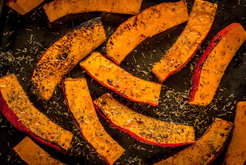 Traditional autumn dishes from pumpkin. Fried baked on grill pumpkin with spices, olive oil, herbs. On a baking sheet, on a rustic wooden old table. Top view copy space