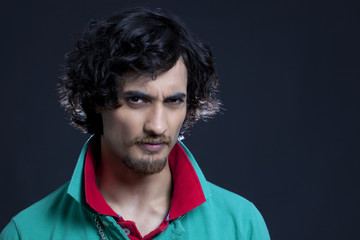 Portrait of young Indian man against black background 