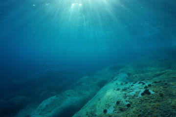 Natural sunlight underwater through water surface in the Mediterranean sea on a rocky seabed,...