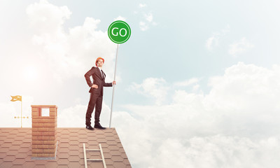 Businessman in suit on house top with ecology concept signboard.