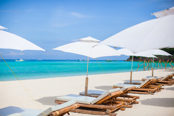 Fototapeta na wymiar Beach chairs and umbrella on exotic tropical white sandy beach