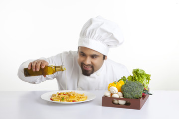 Chef pouring olive oil on pasta