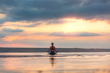 Pretty woman doing yoga at sunset outdoors