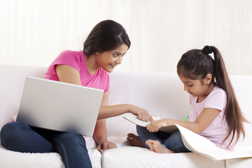 Happy young woman assisting her daughter in drawing 