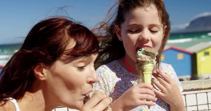 Mother and daughter having ice cream at beach