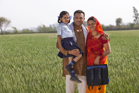 Portrait of a happy family of three standing together with field in background 