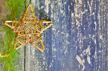 Wooden glitter star and larch branch on the old white and blue patina wooden board as a background. Christmas, New Year card. Place for text. Top view.
