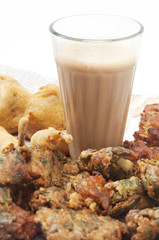 Glass of chai with pakoras , bhajiyas and fried potato balls isolated over white background 