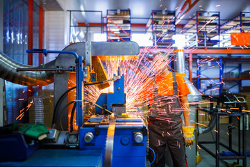A male mechanic working on welding machine in the Industrial production of metal products. Sparks...