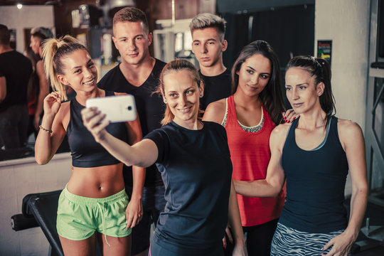Happy young people taking selfie at the gym after workout