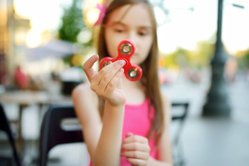 Cute school girl playing with colorful fidget spinner