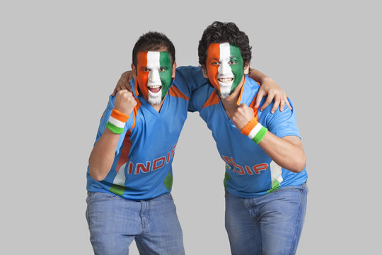 Excited male cricket supporters with face painted in tricolor cheering over colored background 