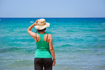 Fototapeta na wymiar girl with a hat looking at the sea, Sardinia. Italy