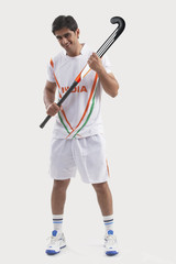 Full length portrait of happy young man holding hockey stick isolated over gray background