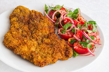 large beef schnitzel with tomato, onion, and parsley