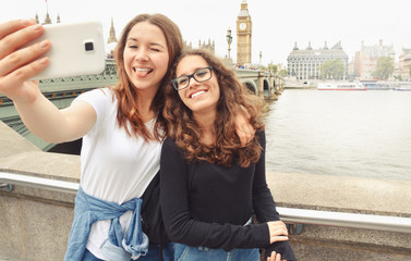 Happy smiling pretty teenage girls taking selfie at Big Ben, London
