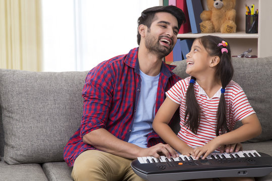 Happy Father And Daughter Playing Piano