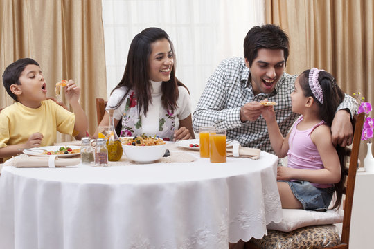 Family having fun while eating pizza together at restaurant 