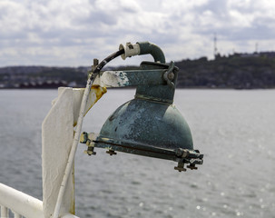 Close up of green metal lamp with rust on a ship
