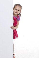 Cute little girl standing by blank billboard 