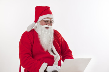 Naklejka premium Santa Claus operating laptop over white background 