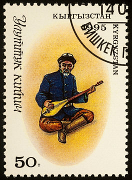 Man in traditional Kyrgyz clothes with comus on postage stamp