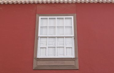 Fenster mit Fensterladen und roter Fassade