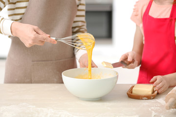 Mother and daughter cooking on table in light kitchen