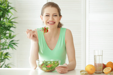 Young woman using mobile phone for counting calories while eating salad. Weight loss concept