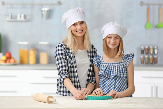 Mother and daughter cooking on table in kitchen