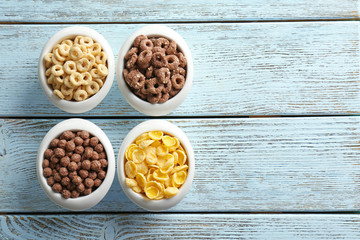 Bowls with different healthy breakfast cereals on wooden background