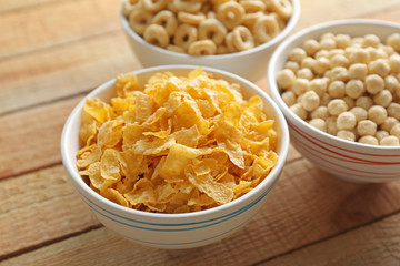 Bowls with different healthy breakfast cereals on wooden background