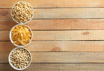 Bowls with different healthy breakfast cereals on wooden background
