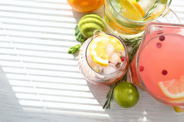 Glass jugs with different lemonades on window sill