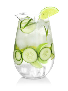 Glass jug of cold lemonade with cucumber and lime on white background