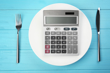 Diet concept. Plate with calculator and cutlery on color wooden background